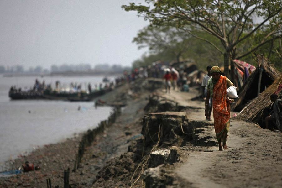 A woman, displaced from her home by a huge storm surge caused by cyclone Aila, carries food distributed by an NGO in Satkhira in southwestern Bangladesh on June 2, 2009 — Reuters/Files