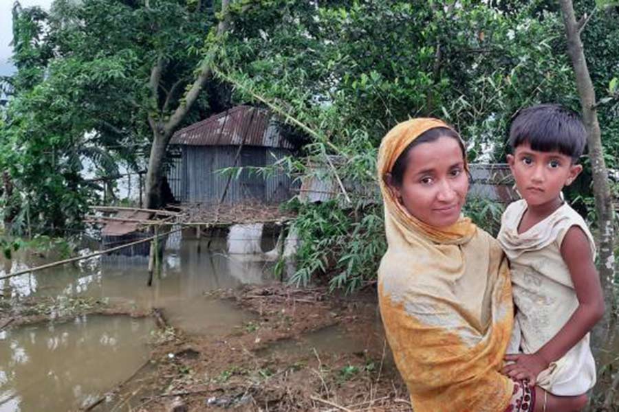 A mother and child standing outside their house that has been inundated in the flood in the Jaintapur area of Sylhet on May 16 this year –UNICEF Photo