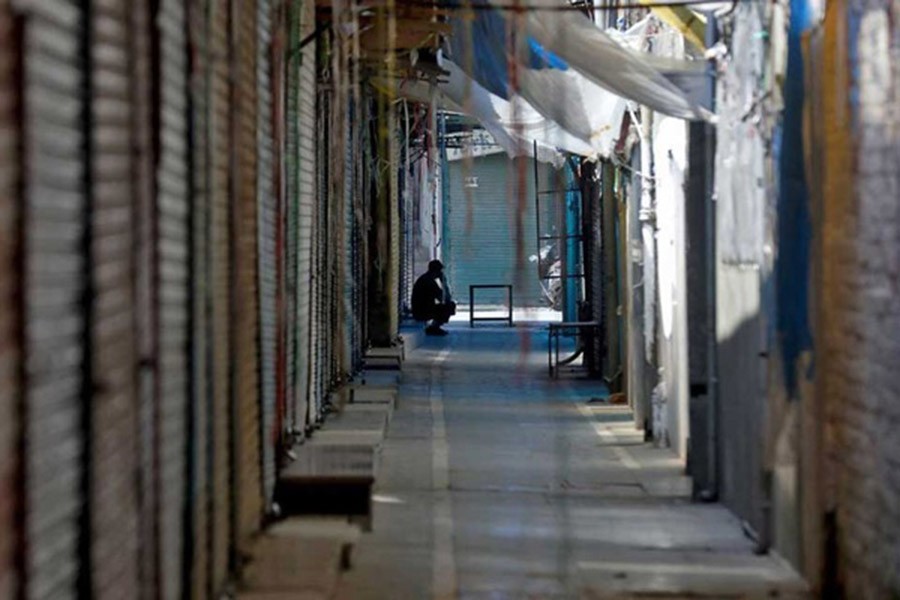 A man sits in front of closed shops during the second day of protesting against the sentencing of Kashmiri separatist leader Yasin Malik, Chairman of Jammu Kashmir Liberation Front (JKLF), near his residence in Srinagar May 26, 2022. Reuters