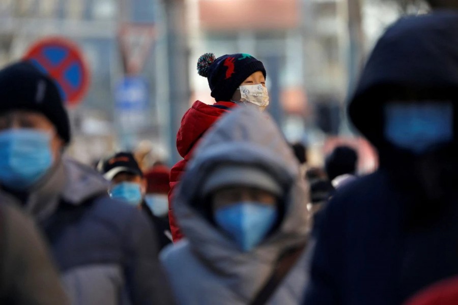 People wearing masks walk in a street in Beijing's central business district (CBD) during morning rush hour, following the coronavirus disease (COVID-19) outbreak, in China December 8, 2020. REUTERS/Tingshu Wang/File Photo