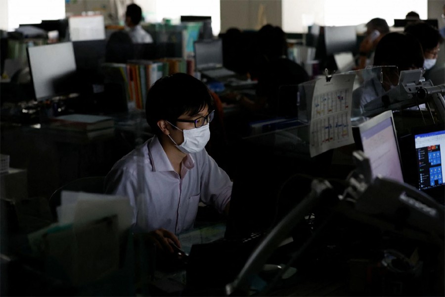 An employee of Tokyo Metropolitan Government office works inside the office with partially switched off lights during daytime to take power-saving measures as Japanese government issues warning over possible power crunch due to heatwave in Tokyo, Japan on June 30, 2022— Reuter photo