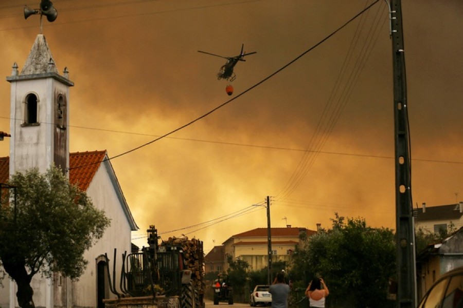 A fire fighting helicopter works to contain a wildfire in Leiria, Portugal July 13, 2022. Reuters