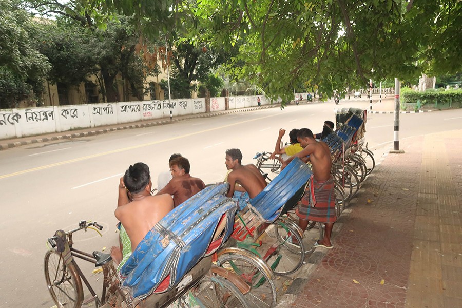 Rickshaw pullers taking rest under the trees during a hot summer day in Dhaka — FE photo