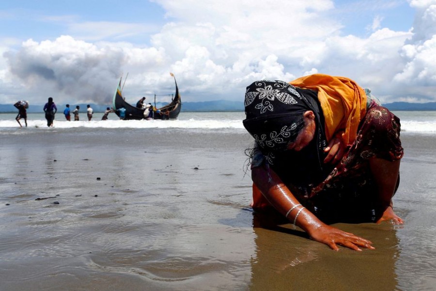 An exhausted Rohingya refugee woman touches the shore after crossing the Bangladesh-Myanmar border by boat through the Bay of Bengal in Shah Porir Dwip, Bangladesh, September 11, 2017. Picture taken September 11, 2017. REUTERS/Danish Siddiqui/File Photo