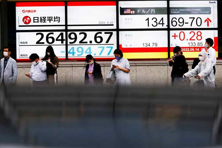 People are seen in front of a screen displaying the Japanese yen exchange rate against the US dollar and Nikkei share average in Tokyo on June 14 this year –Reuters file photo