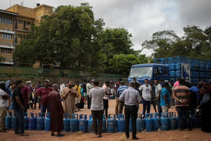 People stand next to their empty cylinders as they wait in a queue to buy domestic cooking gas, amid the country's economic crisis, in Colombo, Sri Lanka, Jul 23, 2022. REUTERS