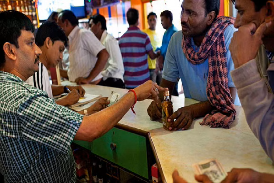 Customers buy Indian alcohol (whisky) in a liquor shop (wine shop) in Nagoa Beach, Diu, India. Alamy via Reuters Connect