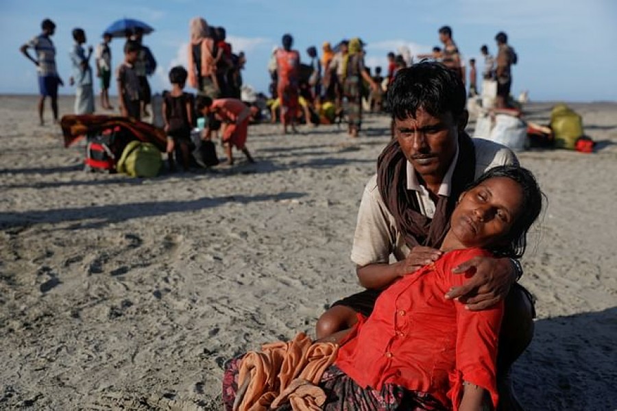 Arif Ullah, who said his village was burnt down and relatives killed by Myanmar soldiers, comforts his wife Shakira who collapsed from exhaustion as Rohingya refugees arrive by a wooden boat from Myanmar to the shore of Shah Porir Dwip, in Teknaf, near Cox's Bazar in Bangladesh, Oct 1, 2017. |REUTERS/Damir Sagolj