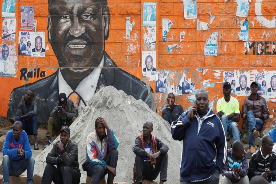 People sit next to a wall mural of Raila Odinga the presidential candidate for Azimio la Umoja and One Kenya Alliance, after the general election conducted by the Independent Electoral and Boundaries Commission (IEBC) in Kibera slums of Nairobi, Kenya August 12, 2022. REUTERS/Monicah Mwangi