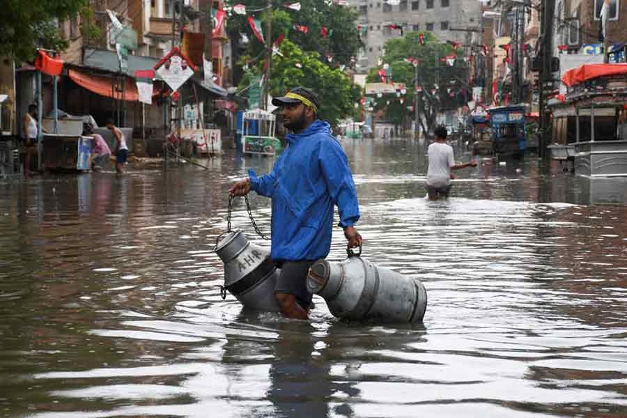 A man with milk-canisters walking along a flooded street in Hyderabad of Pakistan on Wednesday –Reuters photo