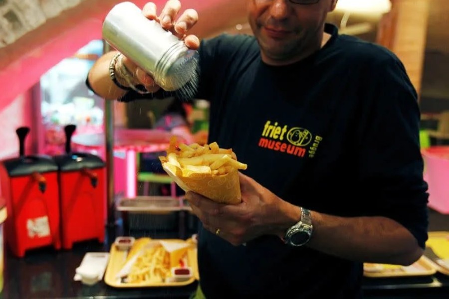 A cook sprinkles salt on fries at a cafe in the Frietmuseum in Bruges - Reuters file photo