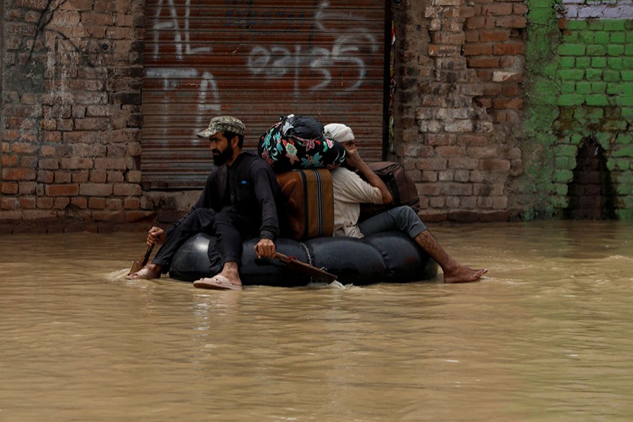 A volunteer paddles an inflatable tube as he evacuates a flood victim with his belongings, following rains and floods during the monsoon season in Charsadda, Pakistan on August 27, 2022 — Reuters photo