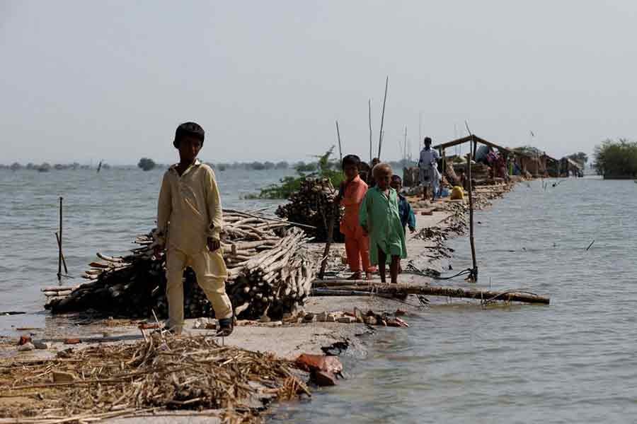 Children standing along a damaged road amid flood following rains and floods during the monsoon season in Bajara village near Manchar lake in Pakistan on September 6 this year –Reuters file photo