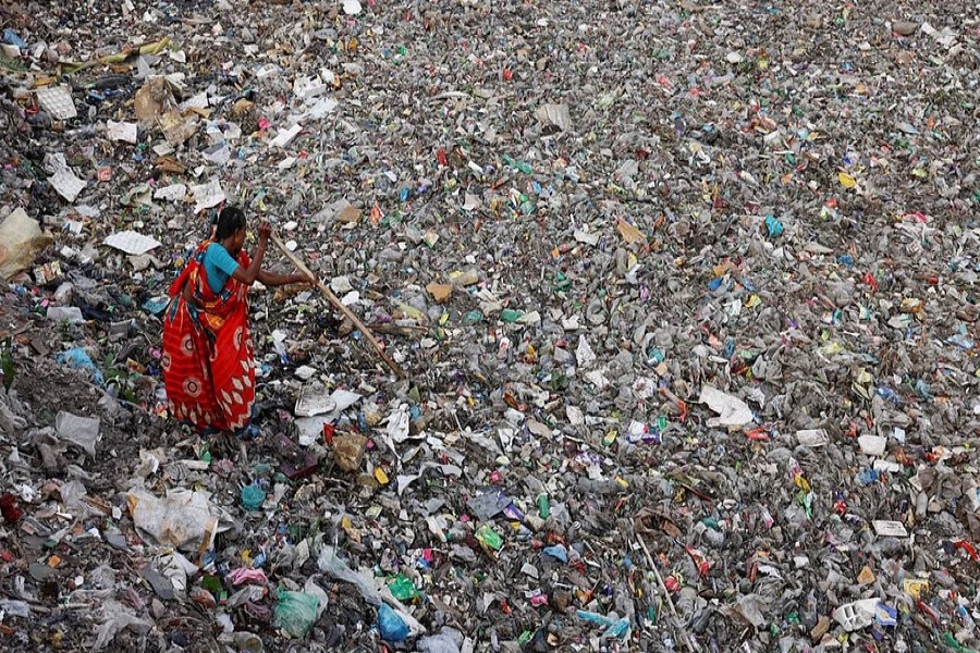 A woman searches for plastic bottles to collect from a canal full of waste in Dhaka, Bangladesh, Aug 11, 2022.REUTERS