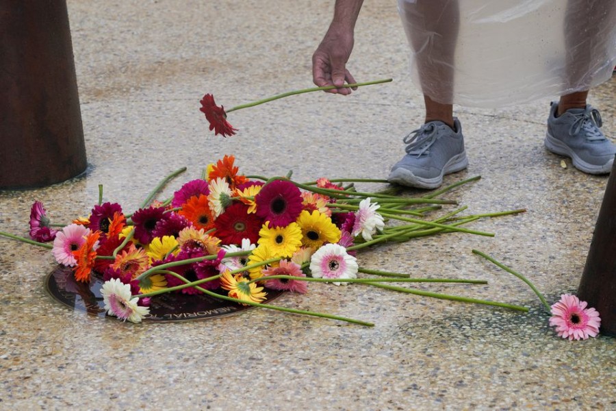 A mourner takes part in a flower laying ceremony during a memorial service to mark the 20th anniversary of the Bali bombings, which killed 202 people including 88 Australians, at Coogee Beach in Sydney, Australia, October 12, 2022. REUTERS/Loren Elliott