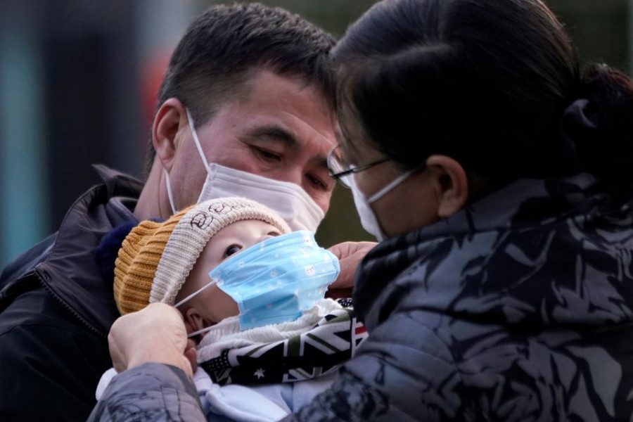 Passengers help a baby wear a mask at the Shanghai railway station in China, as the country is hit by an outbreak of the novel coronavirus, February 9, 2020. REUTERS/Aly Song