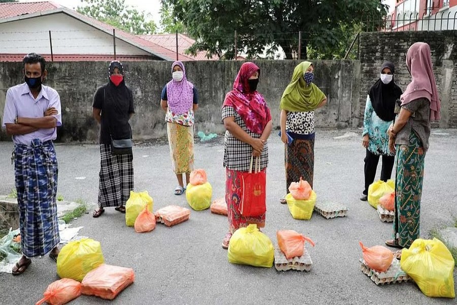 Rohingya refugees wearing protective masks keep a social distance while waiting to receive goods from volunteers, during the movement control order due to the outbreak of the coronavirus disease (COVID-19), in Kuala Lumpur, Malaysia April 7, 2020.REUTERS/Lim Huey Teng/File Photo/File Photo