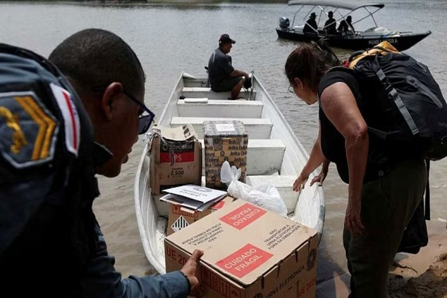 A police officer carries an electronic ballot box to voting polling stations of a community of "ribeirinhos" (forest dwellers), ahead of Brazilian elections, in Sao Raimundo Port, in Manaus, Brazil October 29, 2022. REUTERS