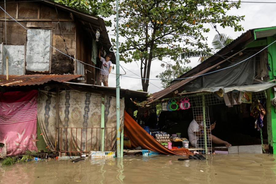 A woman hangs clothes to dry on the roof of her flooded home following heavy rains brought by tropical storm Nalgae, in Imus, Cavite province, Philippines on October 30, 2022 — Reuters photo