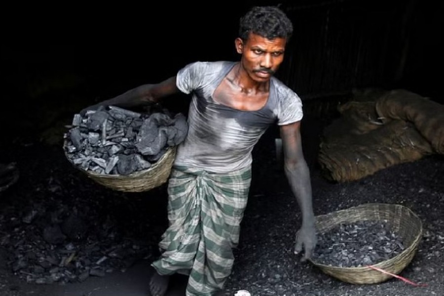 A worker carries coal in a basket in a industrial area in Mumbai, India May 31, 2017. REUTERS