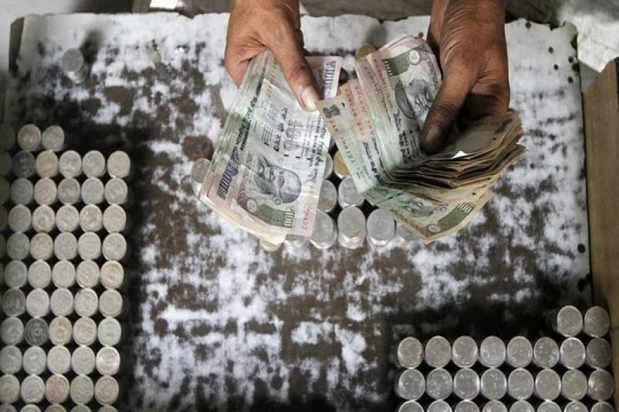 A man exchanging damaged Indian currency counts 100 rupee notes along a roadside in Kolkata August 30, 2013. REUTERS/Rupak De Chowdhuri/Files