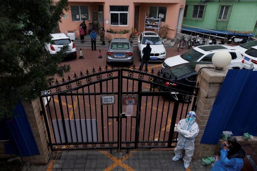 A pandemic prevention worker in a protective suit keeps watch at at residential compound after it was locked down as outbreaks of coronavirus disease (COVID-19) continue in Beijing, November 18, 2022. REUTERS/Thomas Peter