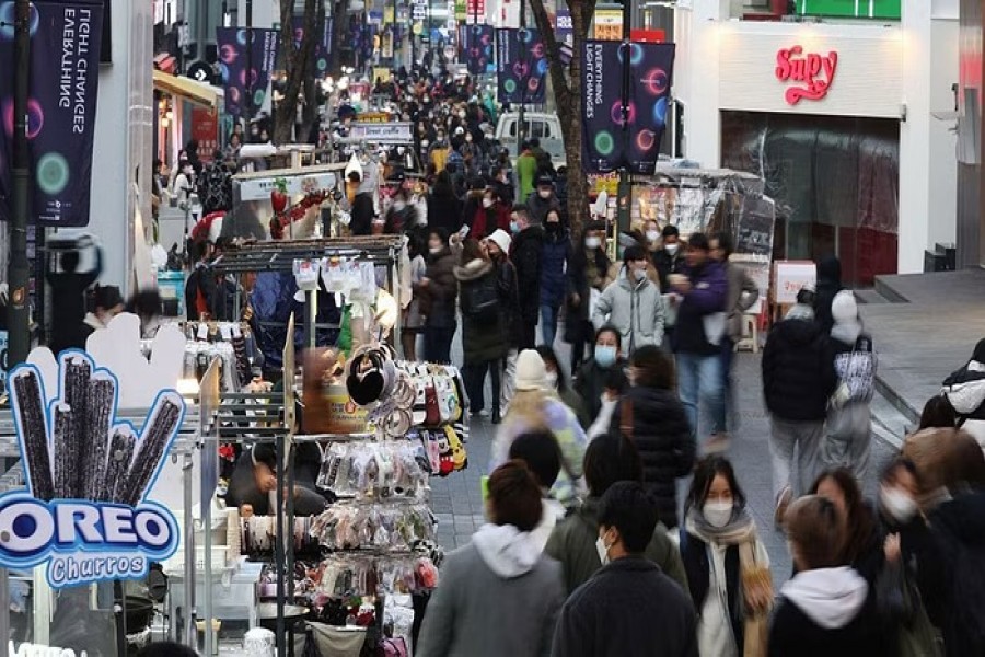 Street vendors (L) wait for customers at Myeongdong shopping district in Seoul, South Korea, Jan 9, 2023.REUTERS