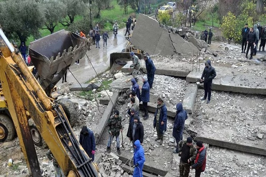 Rescuers stand on rubble of a collapsed building, following an earthquake, in Latakia, Syria, Feb 6, 2023 in this handout image. SANA/Handout via REUTERS