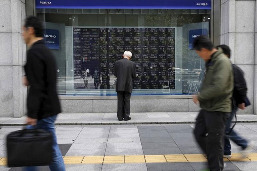 A man looks at a stock quotation board outside a brokerage in Tokyo, Japan, April 18, 2016. Reuters