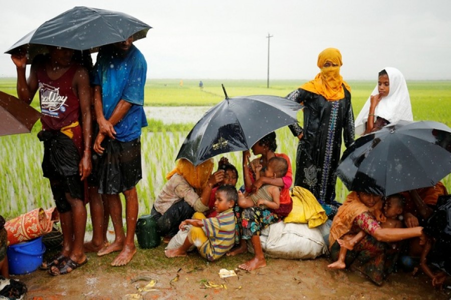 Rohingya refugees with children sit in an open place during heavy rain, as they are held by Border Guard Bangladesh (BGB) after illegally crossing the border, in Teknaf.—Reuters