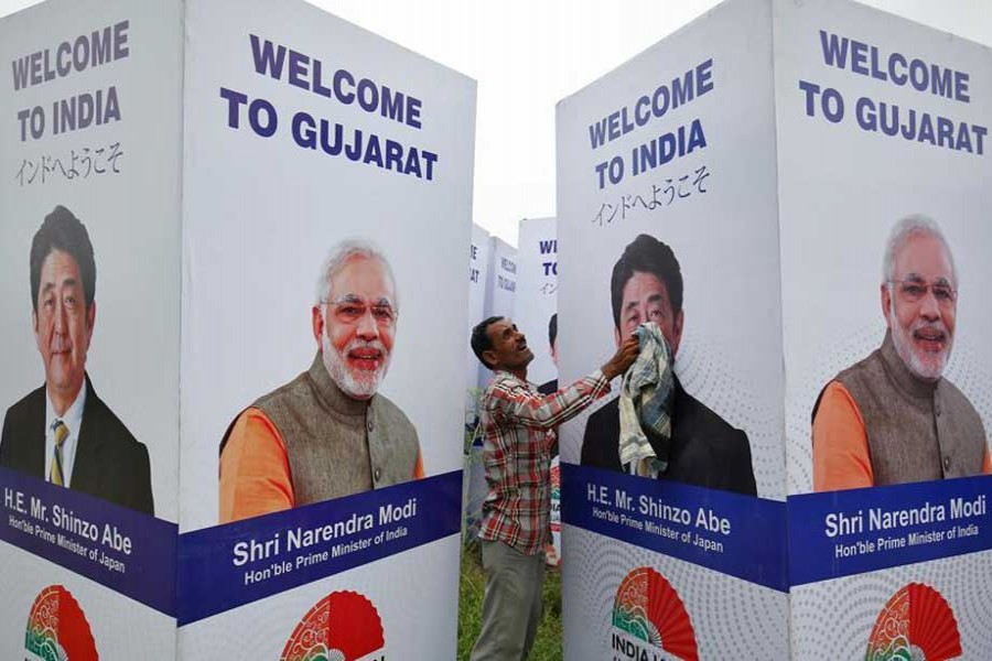 A worker cleans a hoarding featuring Prime Minister Narendra Modi and his Japanese counterpart Shinzo Abe ahead of Abe's visit, in Ahmedabad on September 10.  - Reuters photo