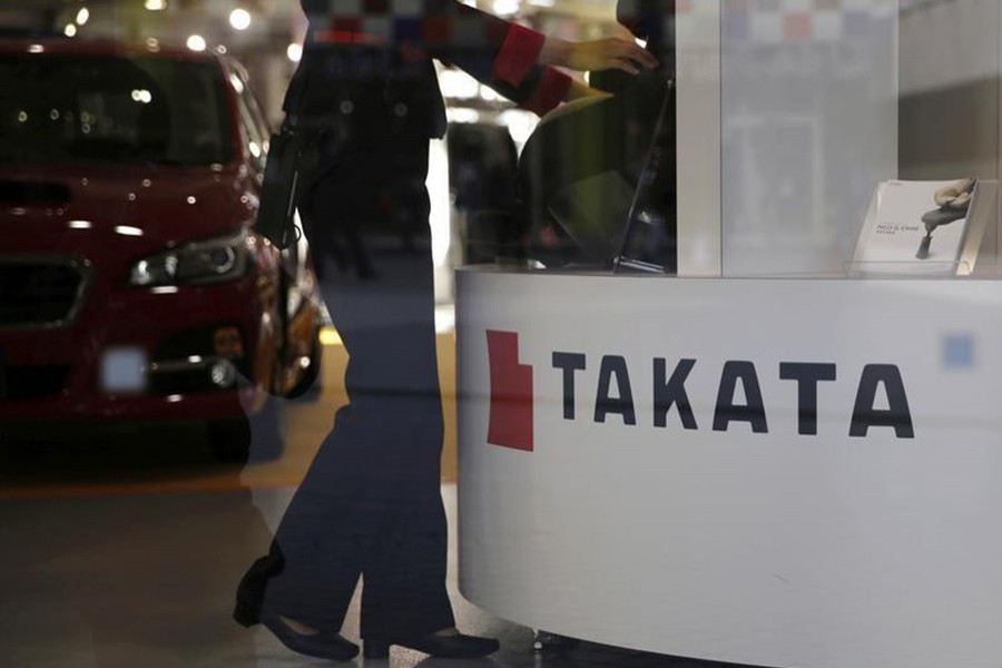 A woman stands next to a logo of Takata Corp at a showroom for vehicles in Tokyo, Japan on November 6, 2015. - Reuters file photo