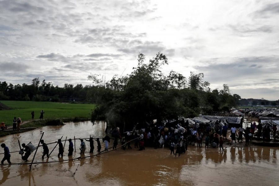 Rohingyas cross a swollen river at a refugee camp in Cox's Bazar, Bangladesh, September 17, 2017. Reuters