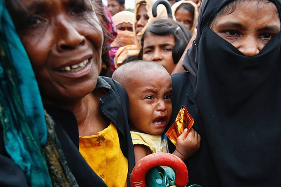 A Rohingya refugee baby cries as his mother jostles for aid in Cox's Bazar of Bangladesh on Sept 20, 2017.
