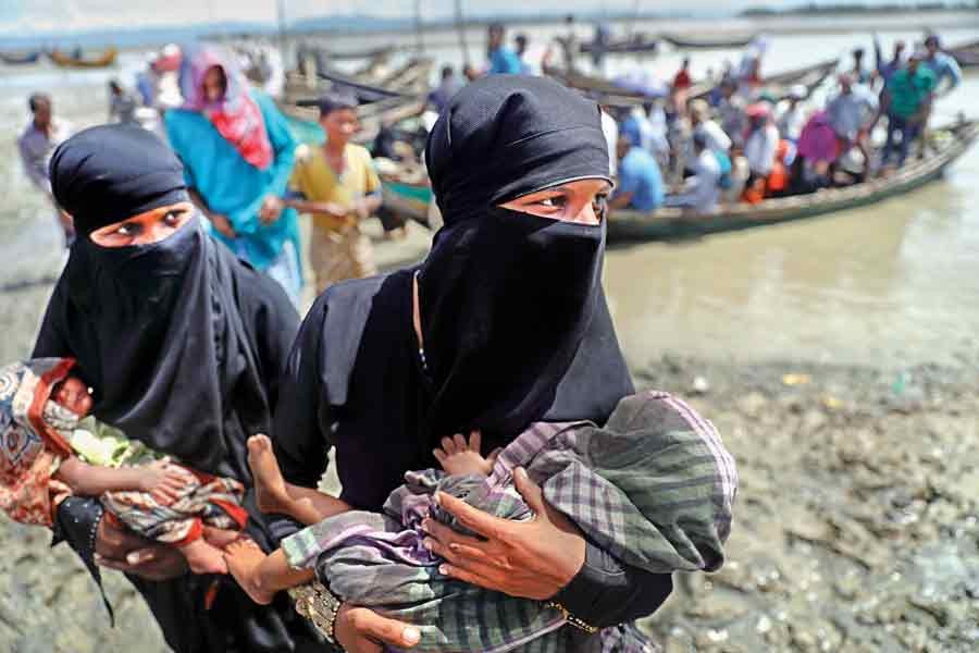 Two Rohingya refugees, who just arrived from Myanmar with their newborn babies, walk towards a relief centre in Teknaf under Cox's Bazar on Tuesday.	— Reuters