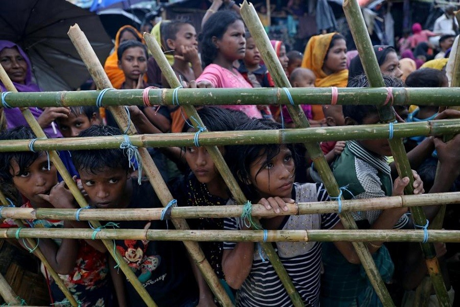 Rohingya refugees look through a fence as they wait outside of aid distribution premises at a refugee camp in Cox's Bazar, Bangladesh October 8, 2017. Reuters