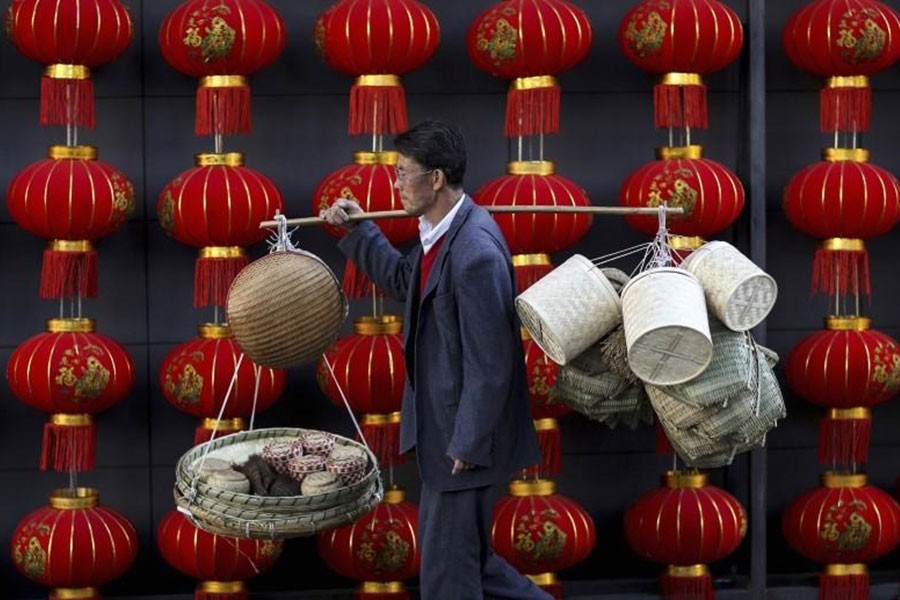 In this file photo, a basket vendor walks past red lanterns serving as decorations to celebrate the new year outside a shopping mall in Kunming, Yunnan province January 6, 2015. - Reuters
