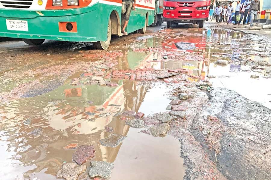 Vehicles negotiate potholes on the main road in the capital's Tejgaon area on Friday. 	— FE Photo