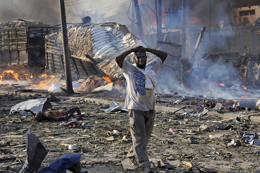 A Somali gestures as he walks past a dead body, left, and destroyed buildings at the scene of a blast in the capital Mogadishu, Somalia on Sunday. - AP photo
