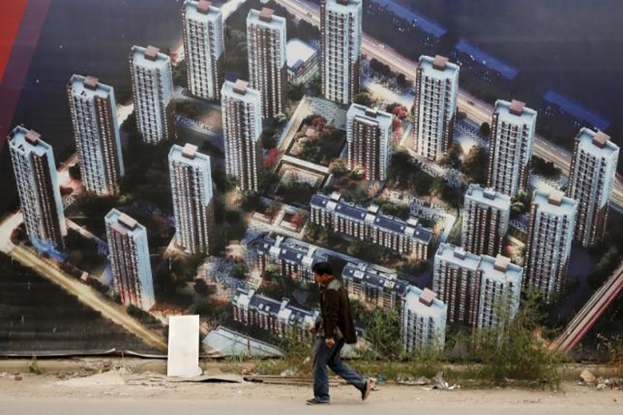 A man walks past a wall at a construction site for a new residential compound at the Binhai new district in Tianjin, China, October 18, 2015. (Reuters)