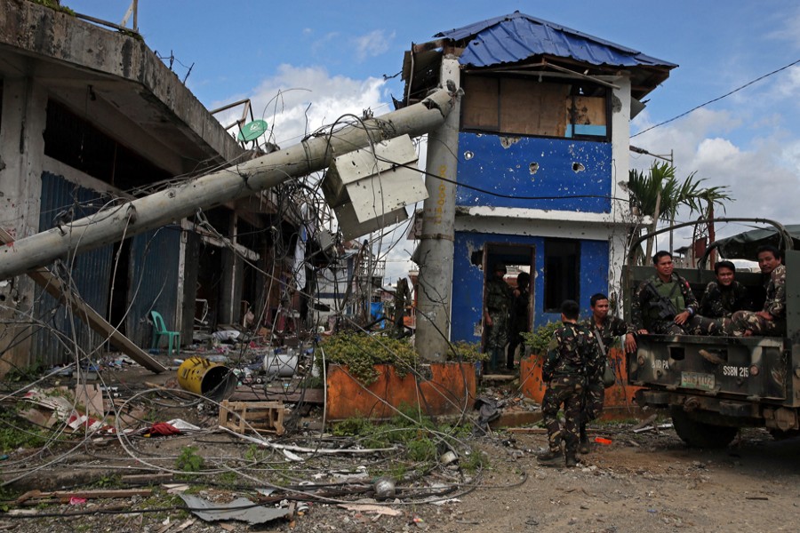 Soldiers stand guard in front of damaged buildings after government troops cleared the area from pro-Islamic State militant groups inside a war-torn area in Bangolo town of Marawi City, Philippines, on Monday. 	— Reuters