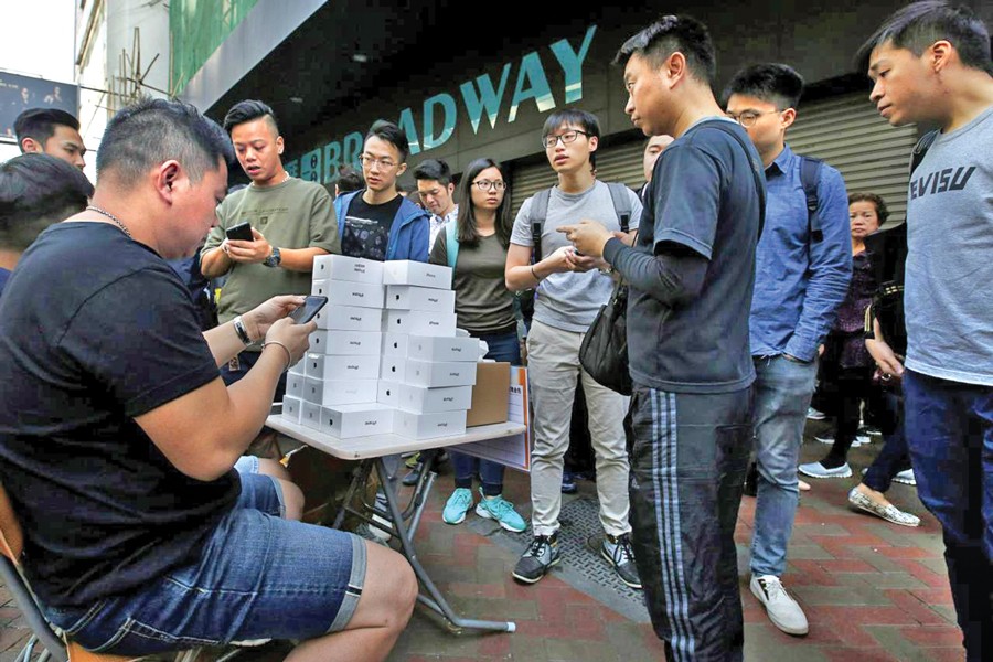 A man pays to buy new iPhone Xs from those who just bought at Apple Stores, on a street in Hong Kong. — Reuters Photo