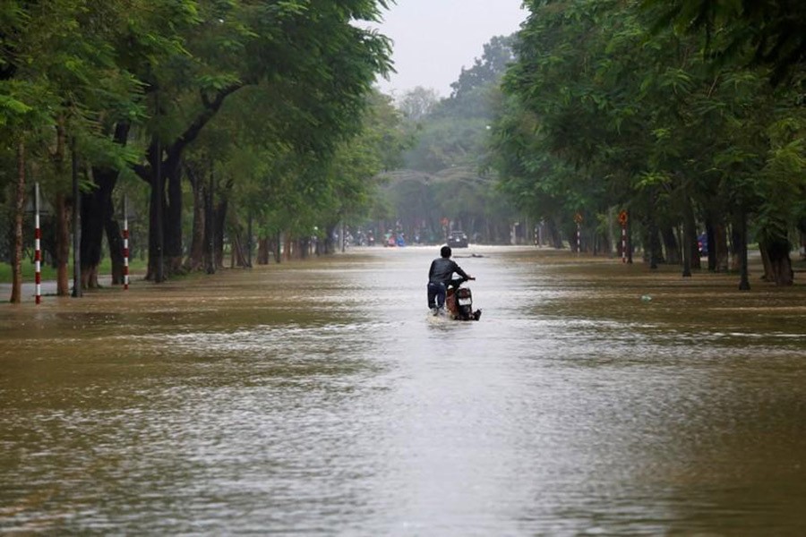 A man pushes his motorcycle along flooded road after typhoon Damrey hits Vietnam in Hue city, Vietnam on Sunday. - Reuters photo