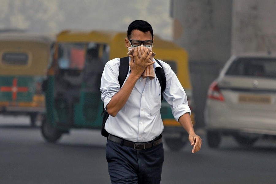 A man covers his face as he walks to work in Delhi, India, November 7, 2017. Reuters