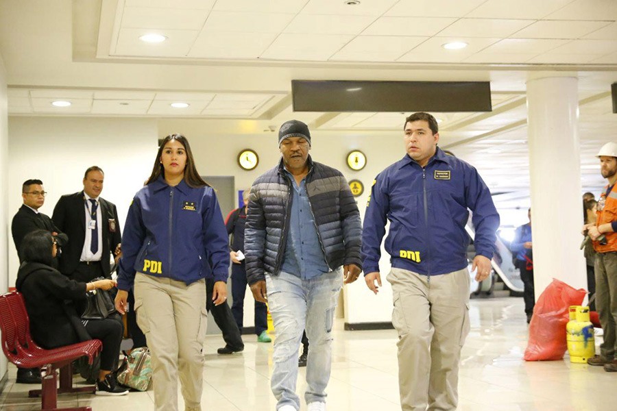 American boxer Mike Tyson (C) is escorted by members of the Investigative Police of Chile (PDI) at the Santiago International Airport in Santiago, Chile on Thursday. - via Reuters