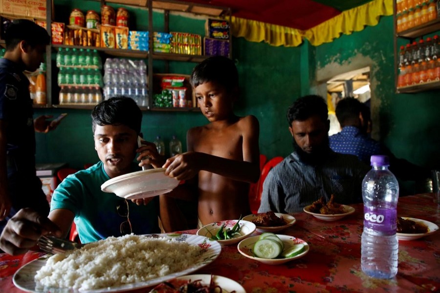 Azimul Hasan, 10, a Rohingya refugee boy, serves plates at a roadside hotel where he works at Jamtoli, close to Palong Khali camp, near Cox's Bazar, Bangladesh, November 12, 2017. Reuters