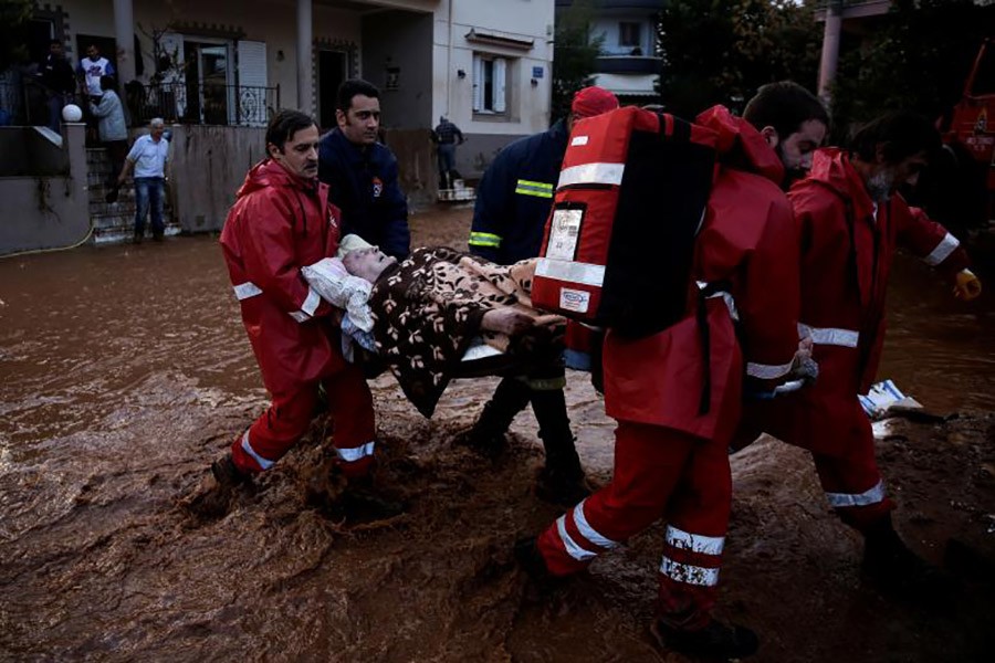Hellenic Red Cross volunteers and firemen evacuate an elderly man following heavy rainfall in the town of Mandra. - Reuters photo
