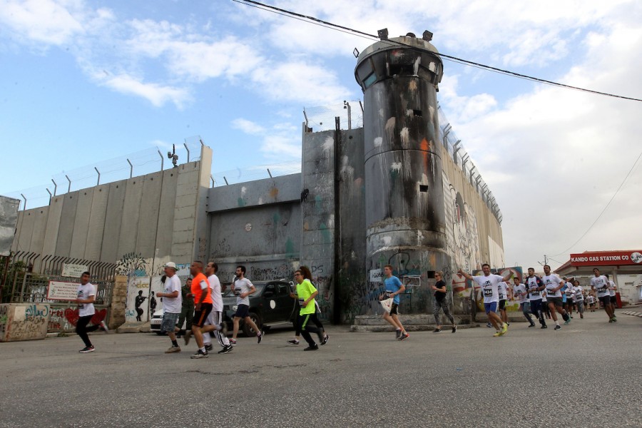 Participants in the 5th Palestine Marathon run along the contentious separation barrier, which divides the West Bank from Jerusalem al-Quds, in Bethlehem on March 31, 2017.  - Photo: Wisam Hashlamoun/APA Images