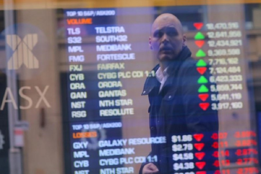 An investor is reflected in a window displaying a board showing stock prices at the Australian Securities Exchange (ASX) in Sydney, Australia, July 17, 2017. Reuters
