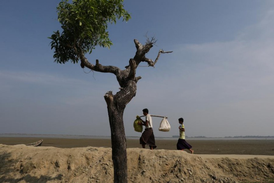 Rohingya refugee Dus Mohammed, 17, carries some of his families belongings after crossing the Bangladesh-Myanmar border at Shah Porir Dwip near Cox's Bazar, Bangladesh, November 23, 2017. - Reuters